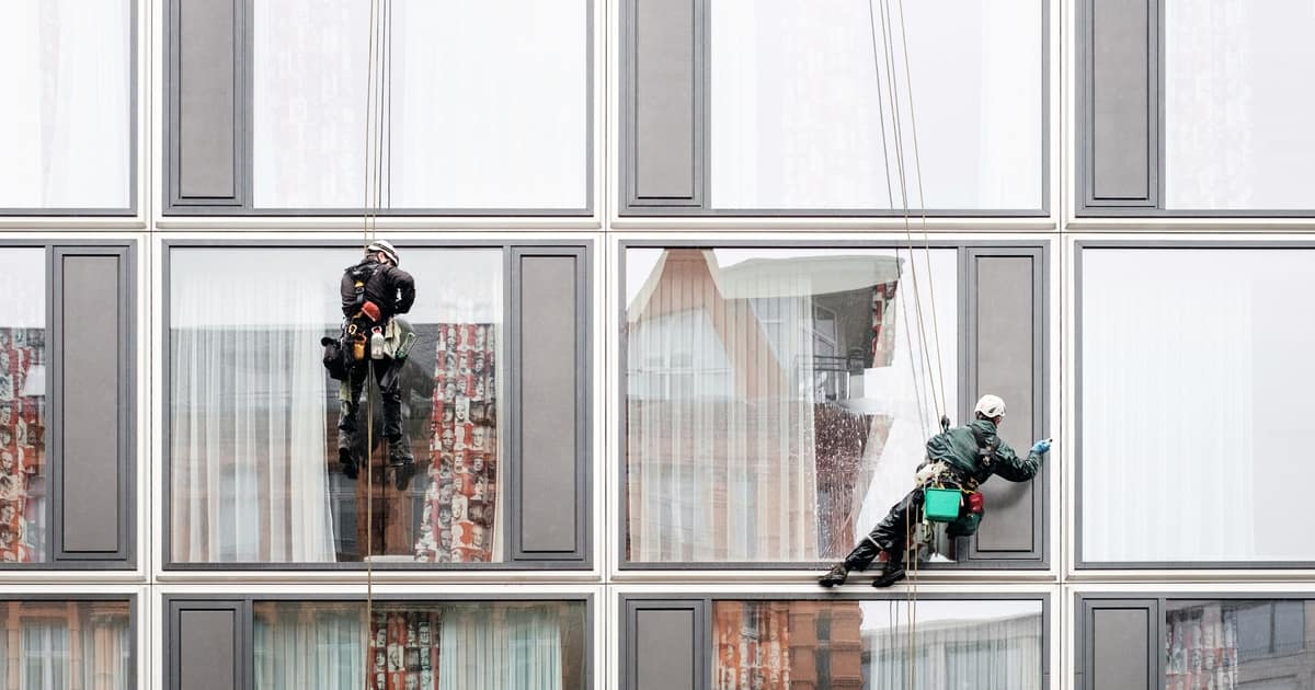Two window cleaners rope down a glass office facade, the hands-on trust work behind citations for cleaning businesses.