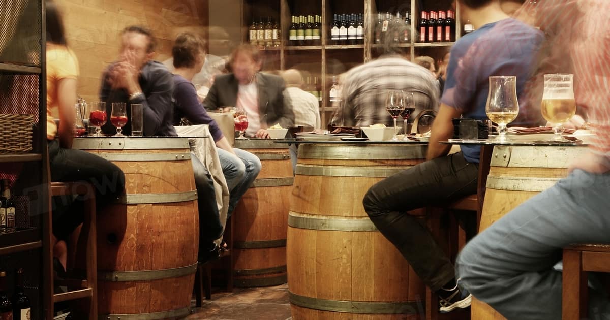 Patrons gather around wine barrels at a rustic bar counter, the lively scene local SEO for bars and pubs depends on.