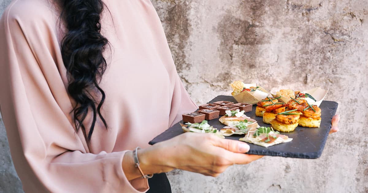 A server presents a tray of gourmet hors d'oeuvres, the kind of detail local SEO for catering should showcase.