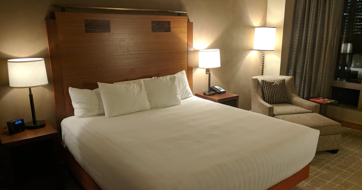 A hotel bed made up with white linens under warm lamp light, the kind of stay local SEO for hotels must own beyond OTAs