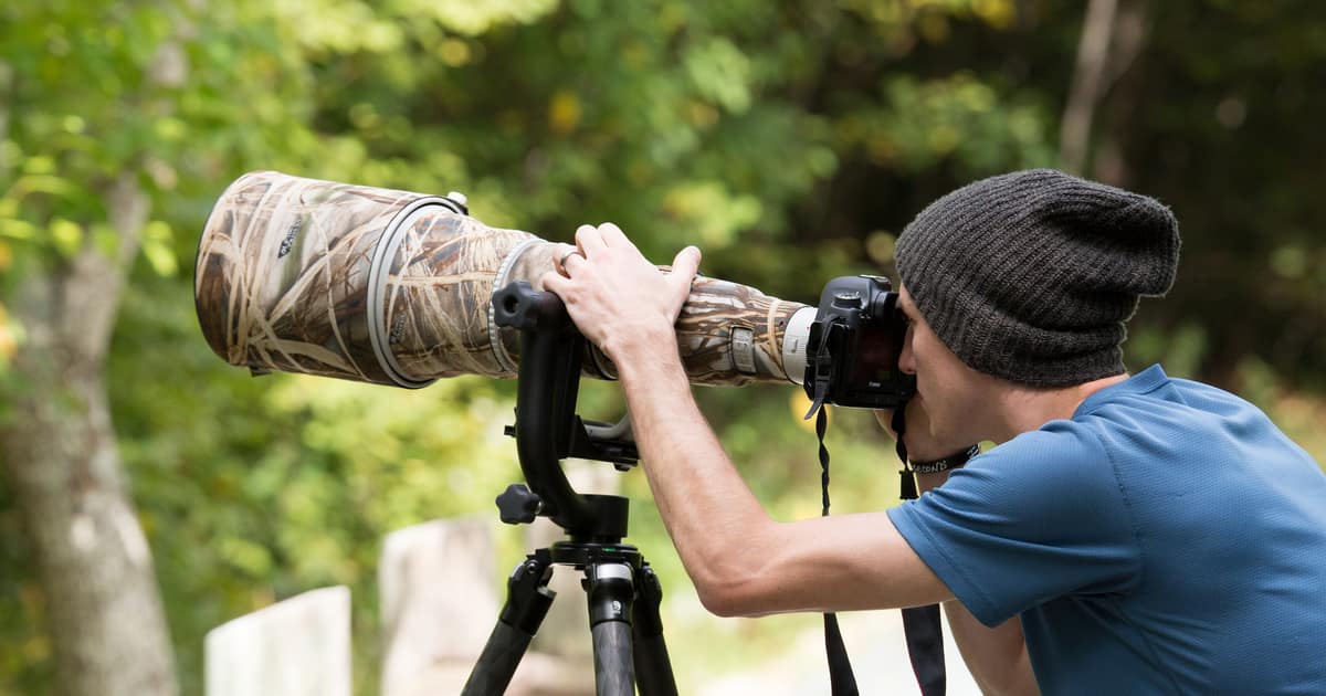 A photographer using a long telephoto lens on a tripod, the kind of work local SEO for photographers still has to locate.