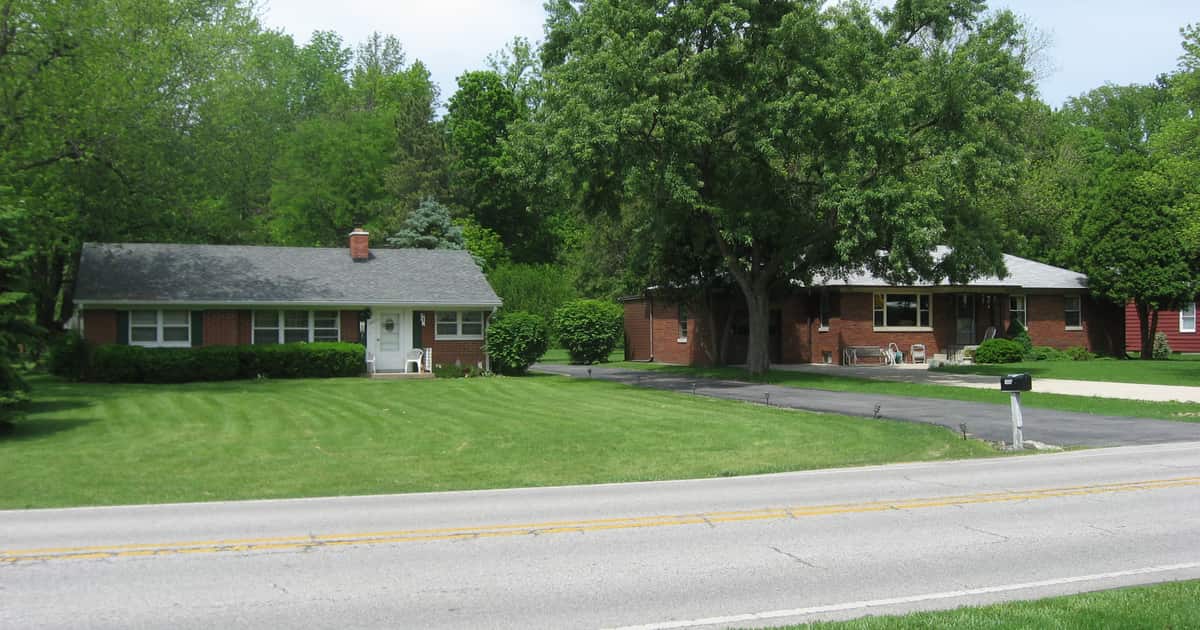 A quiet street with brick ranch houses and lawns, the neighborhood local SEO for real estate agents must be findable in.