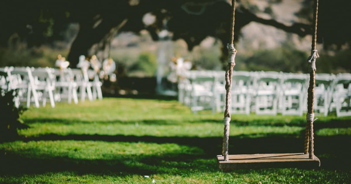 White chairs and a wooden swing set on a lawn for a ceremony, the event local SEO for wedding vendors serves.